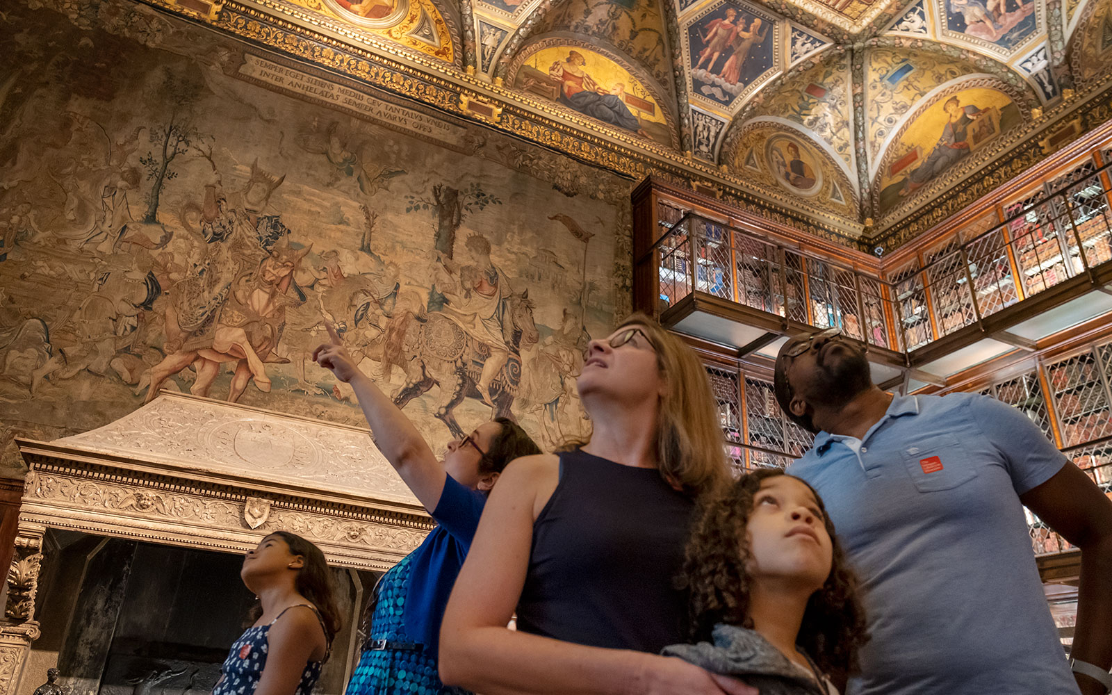 Five figures standing in foreground looking up at ornate ceiling high above them.